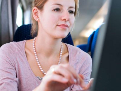 Young woman using her laptop computer while on the train (shallo